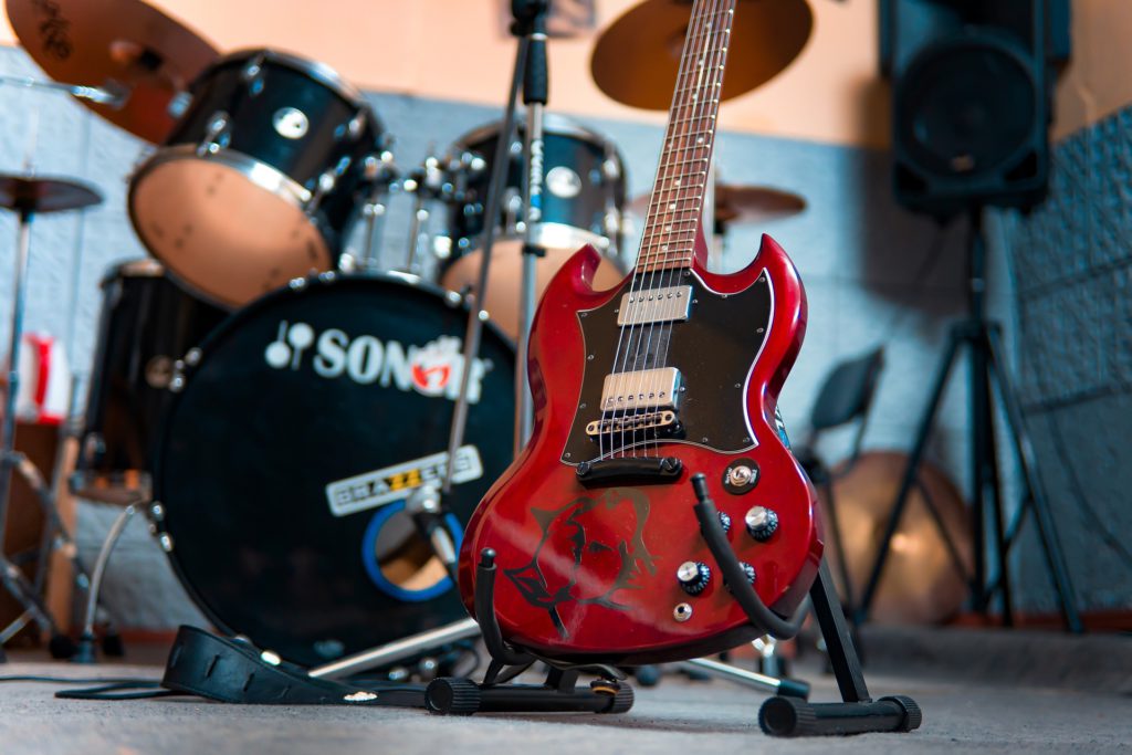 SGタイプのギターがスタジオでスタンドに立てかけられている画像
